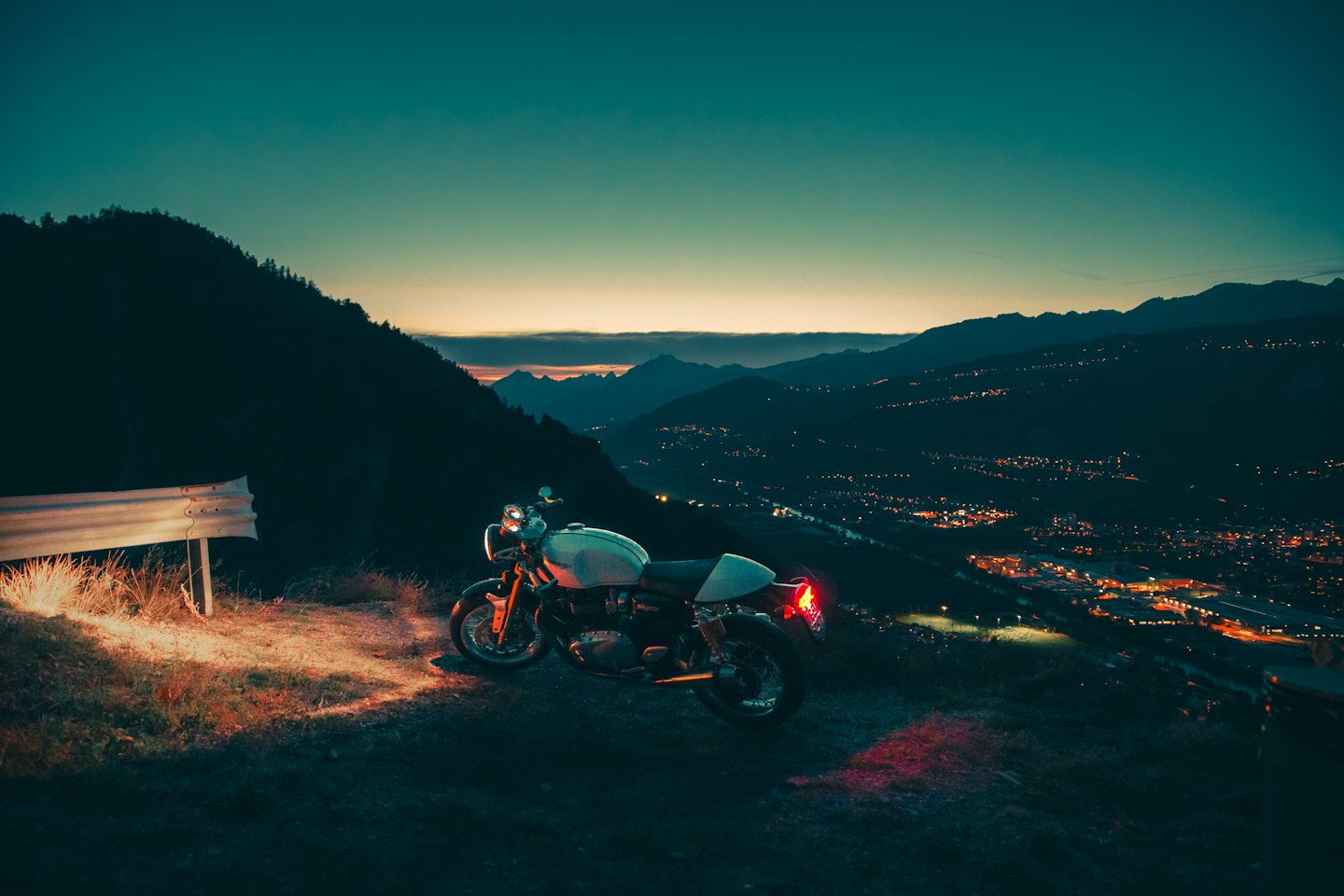 Motocicletta d'epoca parcheggiata su una strada di montagna al tramonto.