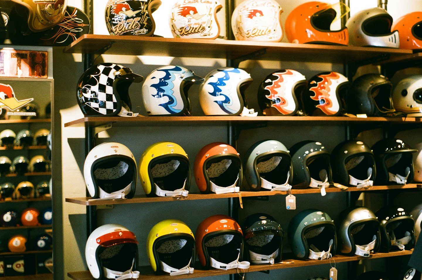 Caschi da moto vintage con design personalizzati su scaffali di legno.